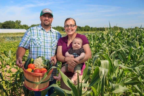farmer and his family standing in field of corn