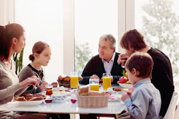 family eats breakfast in condo with many windows