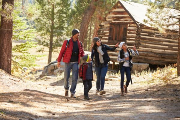 young family walks down a trail to log cabin