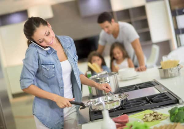 woman cooking for her small family while talking on the phone