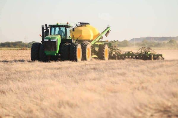 Large green tractor fertilizing crops
