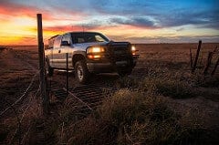 white farm truck driving on farm land at sunset