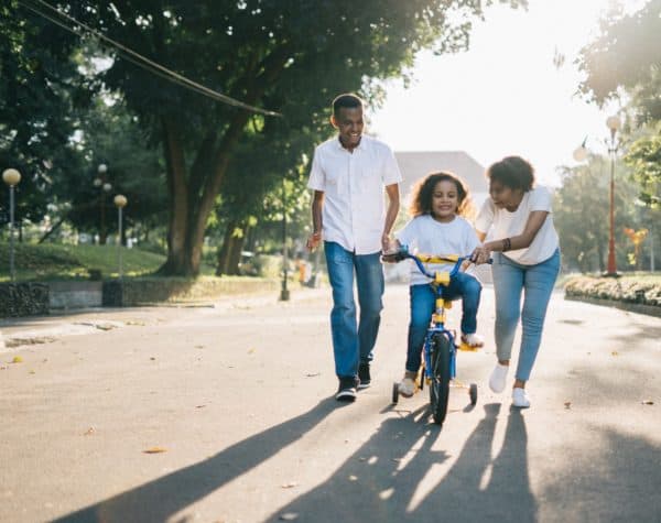 Mother and father help their daughter rider her bike.