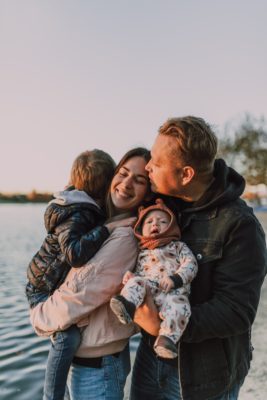 a happy family with two children are smiling near a lake